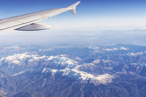 view from the plane window to the snowy peaks of the mountains - 写真・画像