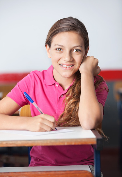 Teenage Schoolgirl Writing At Desk - Фото, зображення