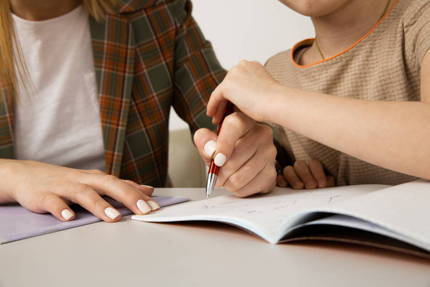 Мама и ребенок делают домашнее задание и пишут за ручкой
. - Фото, изображение