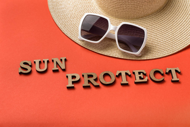 Wort Sonne schützt vor Holzbuchstaben. Sonnenbrille und Hut. lebende Korallen Hintergrund. Reisekonzept - Foto, Bild