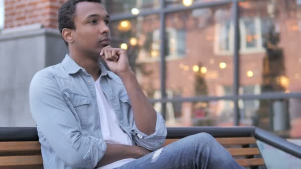 Мислення Африканський чоловік сидить на відкритому повітрі - Кадри, відео