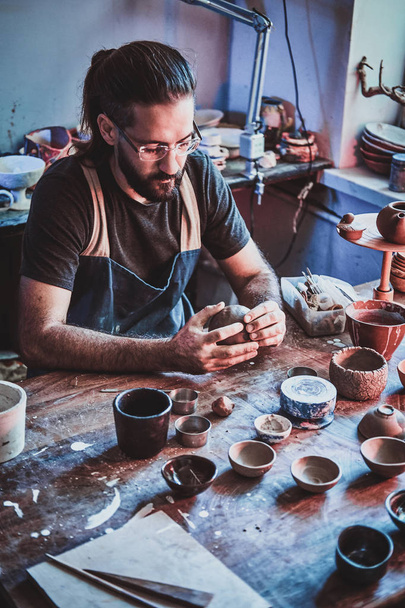 Diligent pensive man in glasses at his  pottery workshop is workig for new project. - Photo, Image