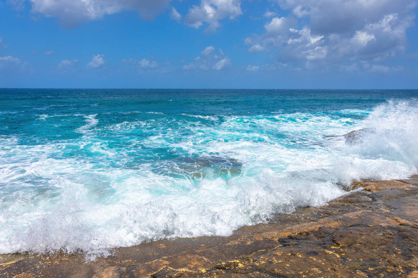 Day storm on a sunny day, turquoise waves of the Mediterranean sea breaking on the rocks. - Photo, Image