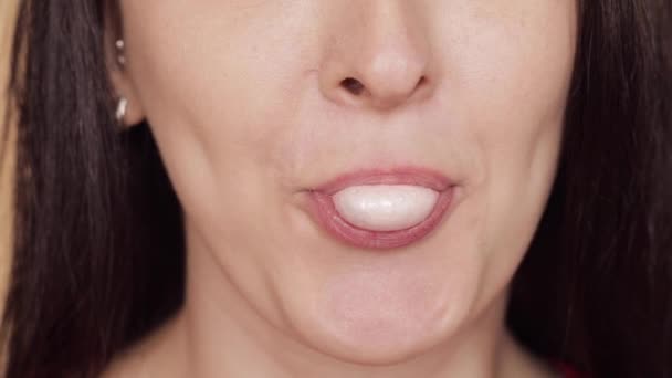 Zijaanzicht van jonge vrouw waait roze kauwgom - Video
