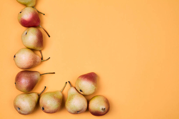 Ripe juicy pears placed on orange background. Colorful fruit pattern or background. - Fotografie, Obrázek