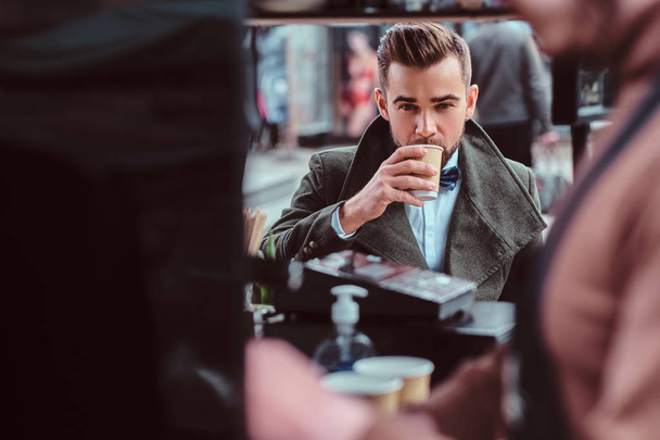 Knappe geprepareerde man geniet van zijn koffie terwijl zittend op coffeeteria - Foto, afbeelding