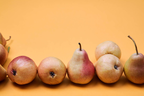 Pears placed as pattern on orange background. Colorful fruit pattern or background - Fotografie, Obrázek