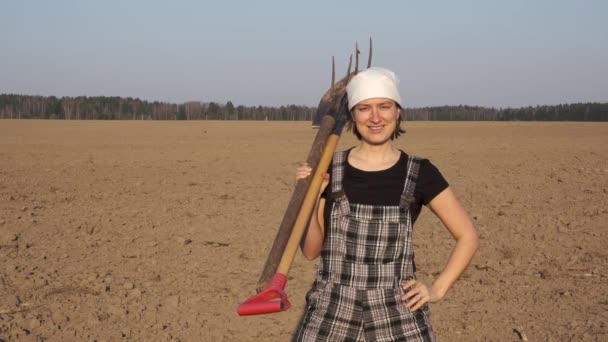 Portrait of female farmer in worker coverall with tools on freshly plowed field on sunset. - Footage, Video