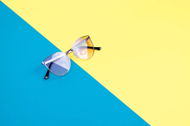 Η έννοια των καλοκαιρινών διακοπών. Κορυφαία προβολή σε γυαλιά ηλίου στο μπλε-κίτρινο φόντο. - Φωτογραφία, εικόνα