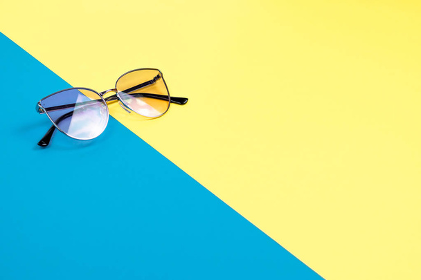 El concepto de vacaciones de verano. Vista superior sobre gafas de sol sobre fondo azul-amarillo
. - Foto, imagen