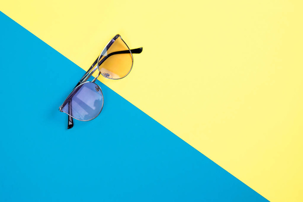The concept of summer vacation. Top view on a sunglasses on the blue-yellow background. - Foto, Imagem