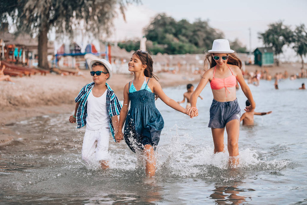 Onnelliset lapset juoksevat yhdessä veden halki ja pitävät
 - Valokuva, kuva