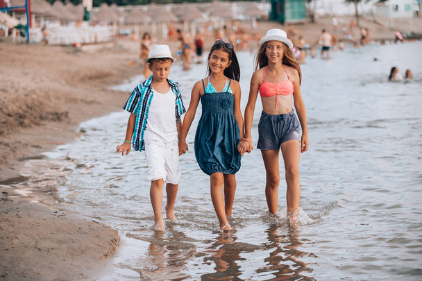 Onnelliset lapset kävelevät yhdessä veden halki
 - Valokuva, kuva