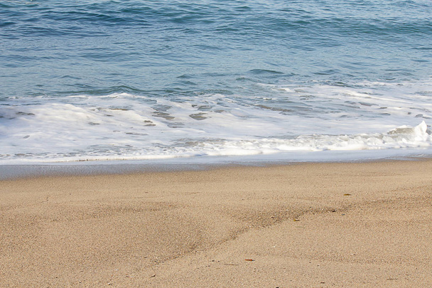 schäumende brechende Welle und Rückspülschaum an einer sandigen Küste - Foto, Bild
