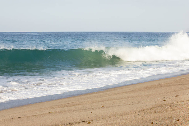 fröccsenő hullám feltörése duzzanat hullám hab a öblítésű homokos strandon - Fotó, kép