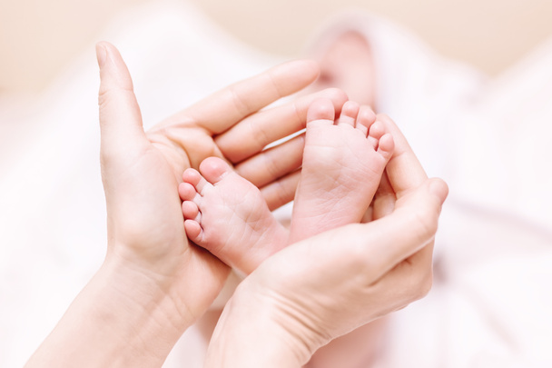 Mother holding newborn baby feet in hands. Mom taking care about infant child after taking bath. Parents childcare. Children healthcare and happy family - Photo, Image