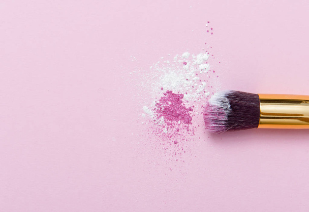 Make-up Pinsel auf rosa Hintergrund mit buntem Pigmentpuder. Ansicht von oben - Foto, Bild