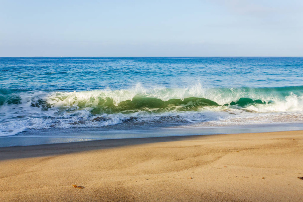 Brechende Welle an der Küste mit Rückspülung, Backspray, mit Sandstrand - Foto, Bild