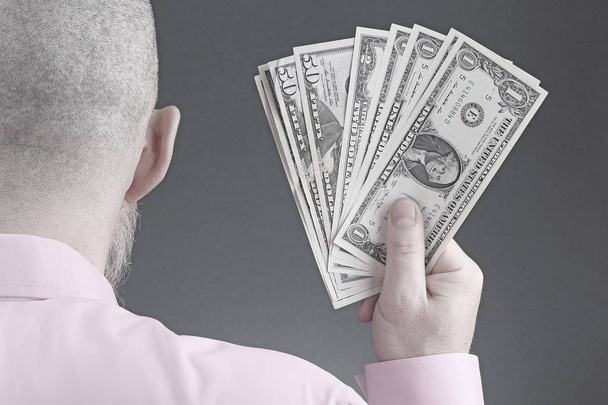 main d'un homme dans une chemise tenant des billets d'un dollar
 - Photo, image