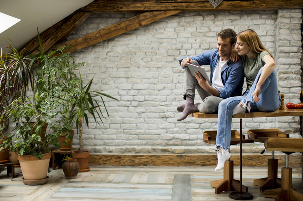 Krásný mladý pár používá digitální tablet a směje se v kuchyni doma - Fotografie, Obrázek