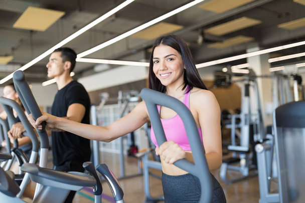 Smiling Latin woman walking on treadmill as it is the best way to stay healthy and fit - Photo, image