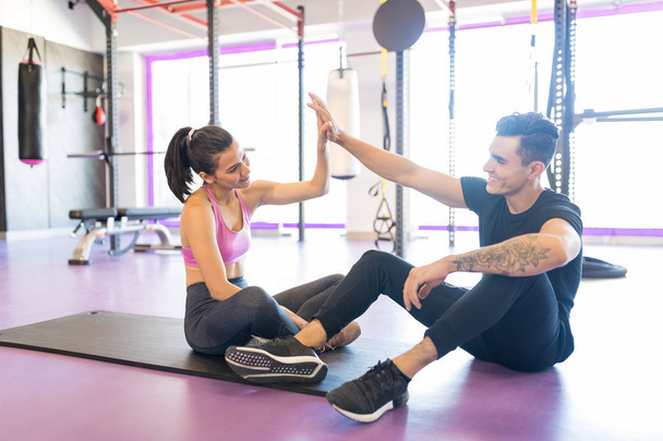Full length of happy fit couple giving high five after workout at gym - Photo, Image