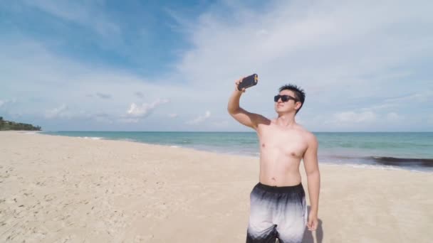 Jovem tirando selfies com seu smartphone na praia, verão. Homem sem camisa, de óculos escuros, tirando fotos na Praia de Tabatinga 2, Conde PB Brasil
. - Filmagem, Vídeo