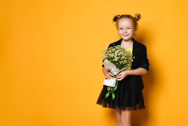 Little cute 5-year-old girl holds a large bouquet of daisies - Foto, afbeelding