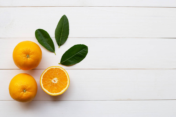 Appelsiinit sitrushedelmät ja vihreät lehdet valkoisella puulla
  - Valokuva, kuva