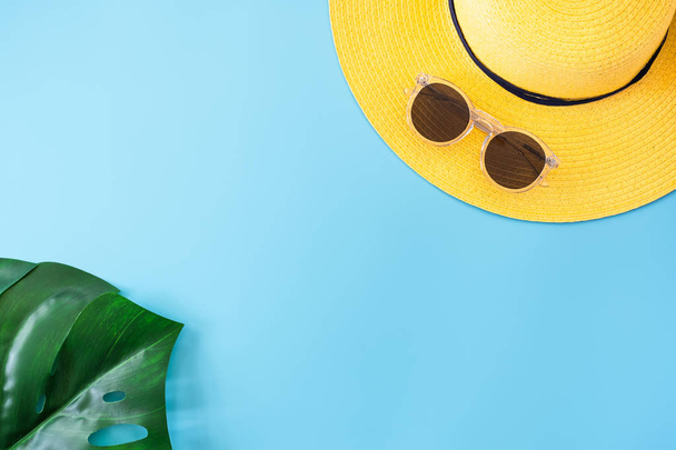 summer blue banner with yellow hat ,sunglasses and monstera leaf on blue background top view. - Foto, Bild