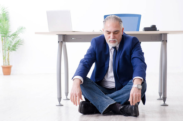 Homem de negócios envelhecido fazendo exercícios de ioga no escritório
  - Foto, Imagem