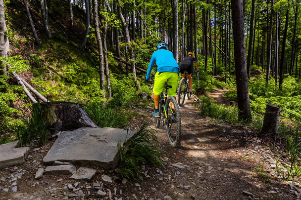 Ciclismo mujer y hombres montando en bicicletas en el atardecer montañas bosque
 - Foto, imagen