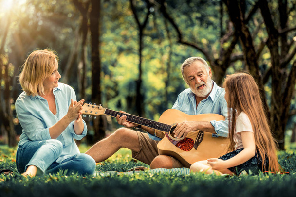 Szczęśliwa rodzina grać na gitarze i śpiewać razem w parku - Zdjęcie, obraz