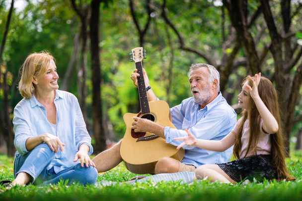 Happy οικογένεια παίζουν κιθάρα και τραγουδούν μαζί στο πάρκο - Φωτογραφία, εικόνα