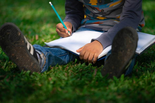 Malé dítě píše na zápisníku v parku. - Fotografie, Obrázek