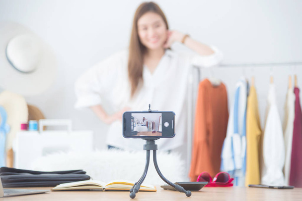Piękna kobieta blogger pokazując ubrania przed kamerą do nagrywania Vlog wideo na żywo w jej sklepie - Zdjęcie, obraz