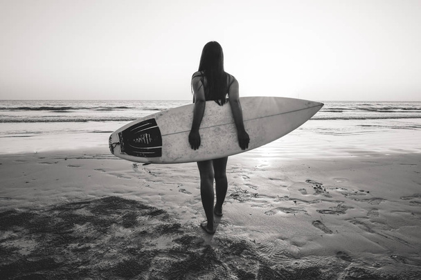 Nostalgie et souvenir photo de surfeuse en bikini aller surfer. belle femme sexy avec planche de surf sur la plage. ton de couleur noir et blanc
. - Photo, image