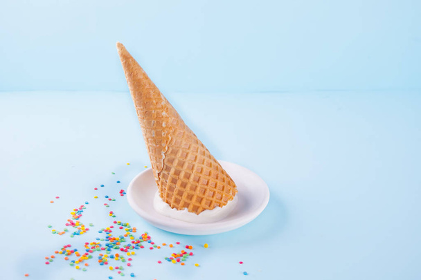 Vanille-ijs met wafel kegels en snoep op de blauwe achtergrond - Foto, afbeelding