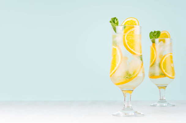 Fresh cold alcohol drink with orange liquor, slices fruit, ice, mint on elegant green color background and white wood board. - Fotó, kép