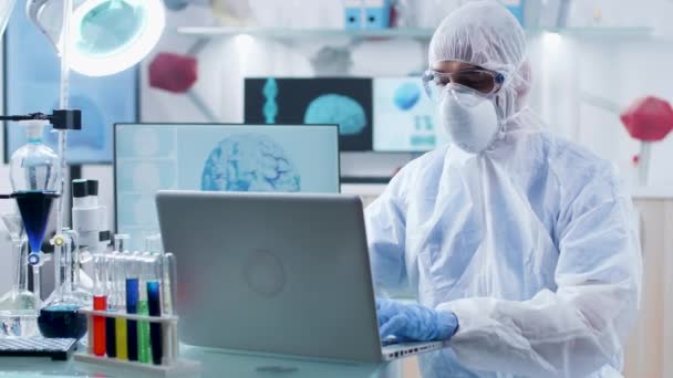 Na moderna instalação de pesquisa, o químico em macacão está trabalhando no laptop
 - Filmagem, Vídeo