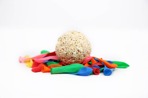 Picture of colorful deflated water balloons and cholai ke ladoo for holi fun. Isolated on the white background. - Photo, Image