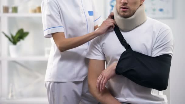 Female surgeon adjusting male patient arm sling, orthopedics and rehab period - Кадры, видео