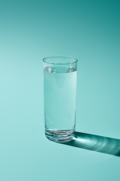 transparent glass with water on turquoise background - Zdjęcie, obraz