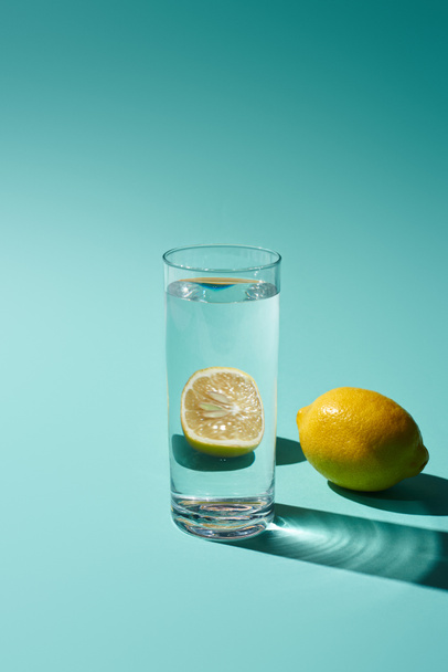verre transparent avec de l'eau et du citron sur fond turquoise
 - Photo, image