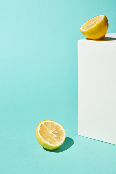 bright lemon halves and white cube on turquoise background - Foto, imagen