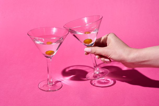 cropped view of woman holding glass of cocktail on pink background - Foto, Imagen
