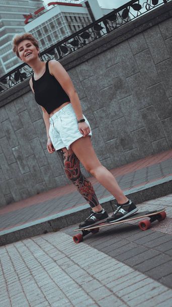 schönes junges Mädchen mit Tattoos mit Longboard - Foto, Bild