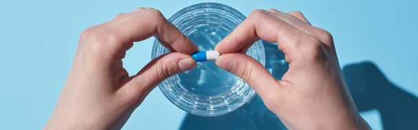 részleges kilátás nő üzembe tabletta üveg vízzel, kék háttér, panoráma lövés - Fotó, kép