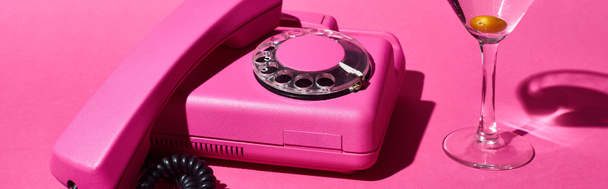 panoramic shot of glass with cocktail and olive near vintage dial phone on pink background - Φωτογραφία, εικόνα