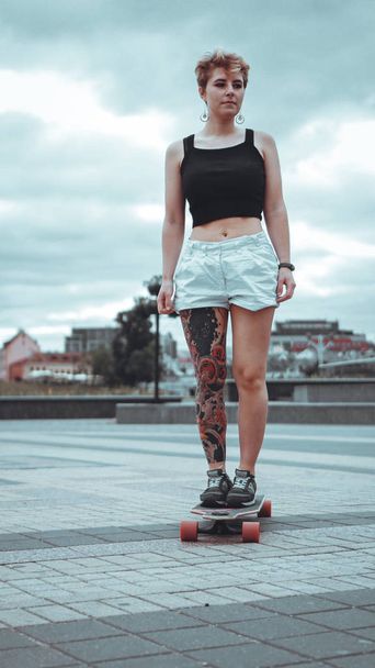 Beautiful young girl with tattoos with longboard - Fotó, kép